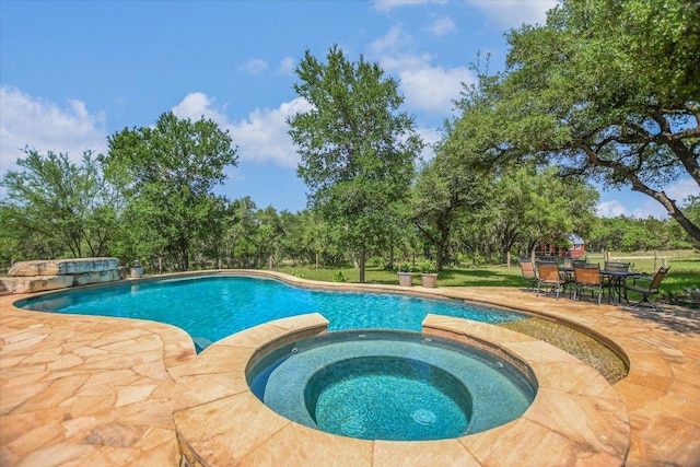 1150 Windmill Run, Wimberley, TX 78676 - view of swimming pool featuring a patio area, outdoor dining area, a pool with connected hot tub, and view of scattered trees