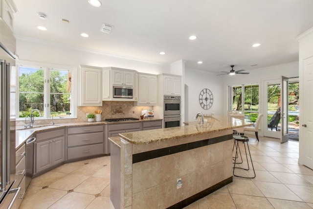 325 Onion Creek Ranch Rd, Driftwood, TX 78619 - kitchen featuring a sink, stainless steel appliances, gray cabinetry, ornamental molding, and light stone countertops