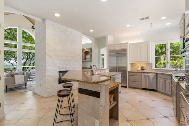 325 Onion Creek Ranch Rd, Driftwood, TX 78619 - kitchen with stainless steel appliances, a ceiling fan, a sink, a kitchen island with sink, and light tile patterned floors