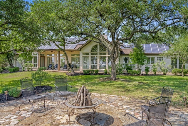 325 Onion Creek Ranch Rd, Driftwood, TX 78619 - rear view of property featuring an outdoor fire pit, a patio, solar panels, and a lawn