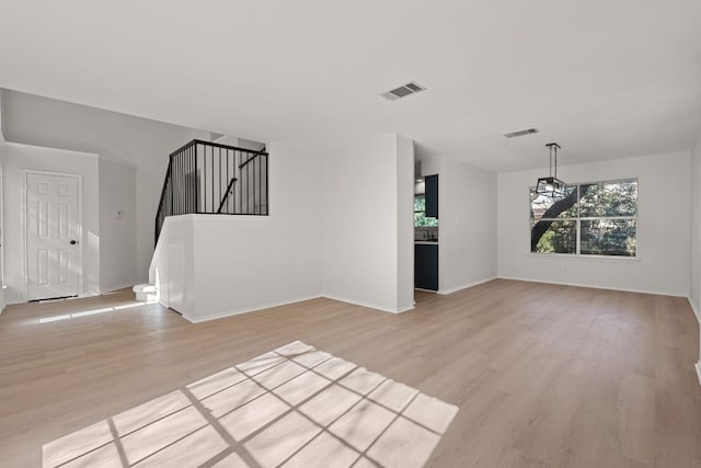 13223 Darwin Ln, Austin, TX 78729 - unfurnished living room with light wood-type flooring, stairs, and baseboards