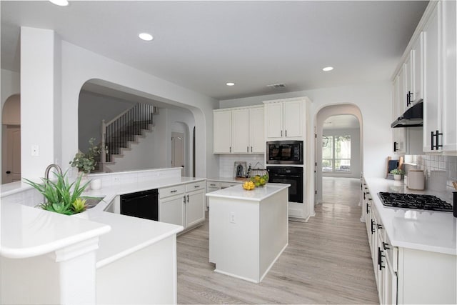 kitchen with arched walkways, black appliances, backsplash, white cabinets, and recessed lighting