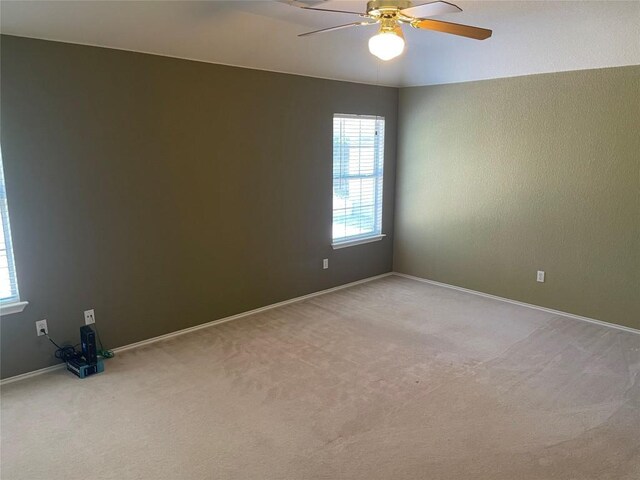 unfurnished room with light colored carpet, ceiling fan, and baseboards