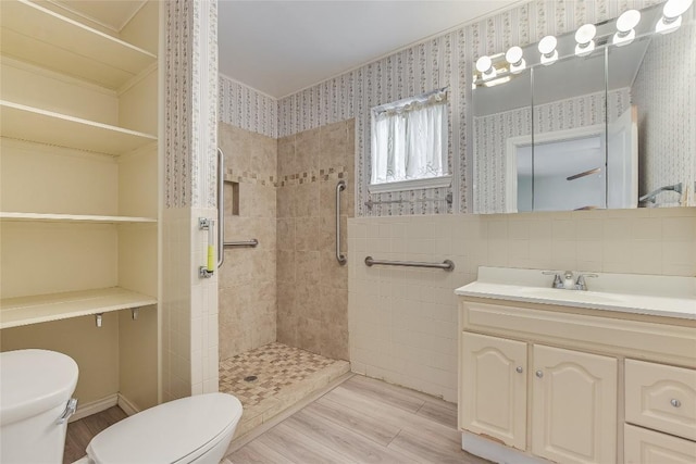 503 Colorado St, Smithville, TX 78957 - bathroom with toilet, a tile shower, wood finished floors, vanity, and wallpapered walls