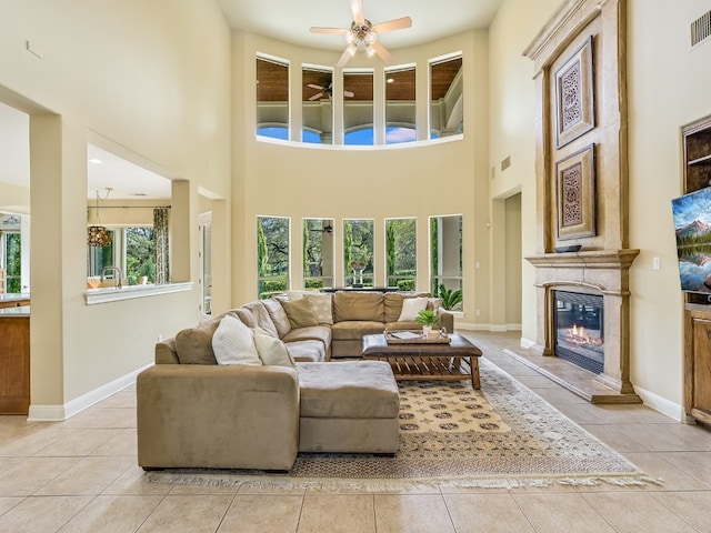 11701 Hunters Green Trl, Austin, TX 78732 - living room featuring a glass covered fireplace, light tile patterned floors, a ceiling fan, and a high ceiling
