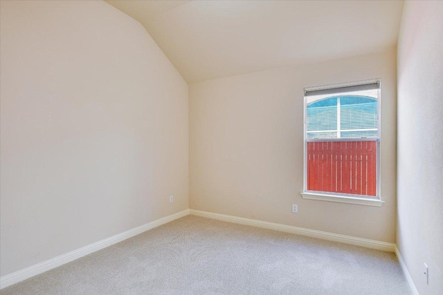 carpeted empty room with lofted ceiling and baseboards