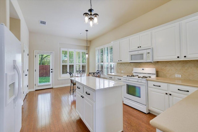 kitchen featuring white appliances, backsplash, plenty of natural light, and light wood-style floors