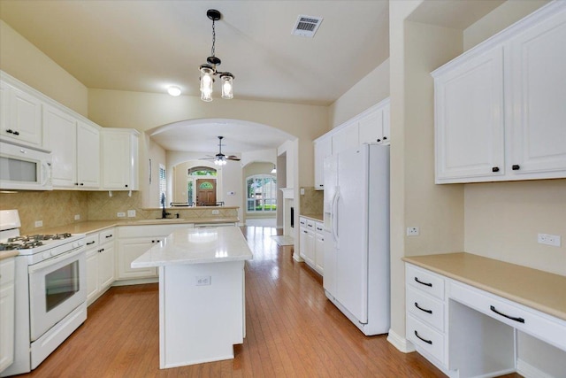 kitchen featuring white appliances, arched walkways, tasteful backsplash, light countertops, and ceiling fan