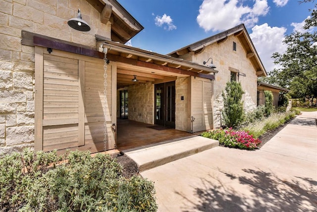 doorway to property with stone siding and a patio
