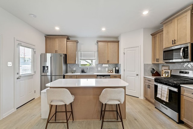 615 Backstays Loop, Kyle, TX 78640 - kitchen featuring stainless steel appliances, a sink, a kitchen breakfast bar, a center island, and light wood-style flooring