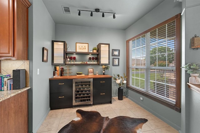 214 Fieldstone Dr, Georgetown, TX 78633 - indoor dry bar featuring beverage cooler, rail lighting, light tile patterned floors, baseboards, and decorative backsplash