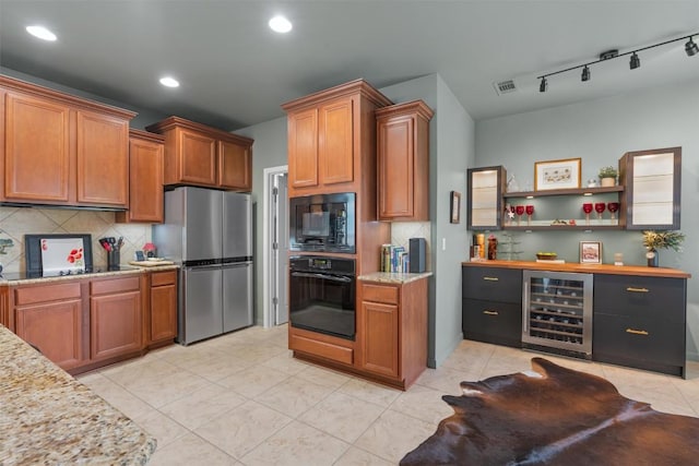 214 Fieldstone Dr, Georgetown, TX 78633 - kitchen with black appliances, beverage cooler, backsplash, brown cabinets, and recessed lighting