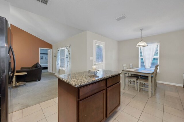 504 Sapphire Ln, Jarrell, TX 76537 - kitchen with black fridge with ice dispenser, light tile patterned floors, light colored carpet, stone counters, and pendant lighting