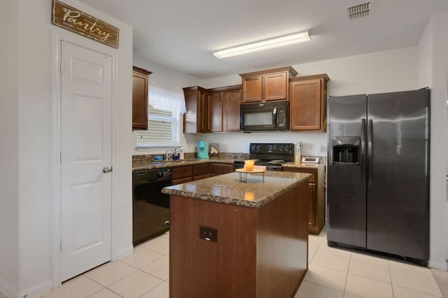 504 Sapphire Ln, Jarrell, TX 76537 - kitchen with black appliances, a kitchen island, light tile patterned flooring, dark stone counters, and a sink