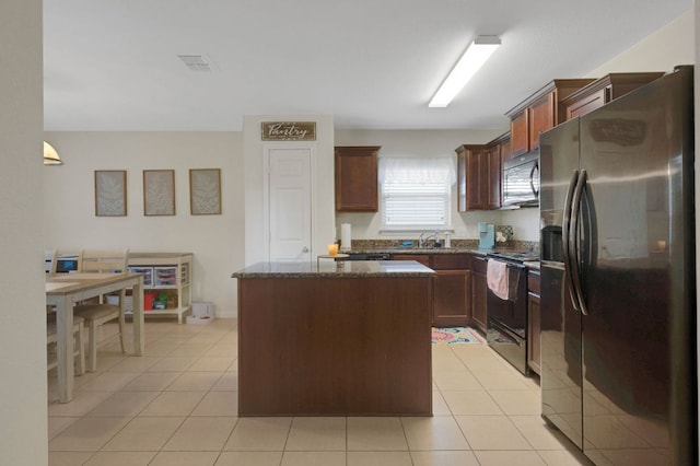 504 Sapphire Ln, Jarrell, TX 76537 - kitchen featuring stainless steel refrigerator with ice dispenser, black electric range oven, a center island, a sink, and dark stone countertops