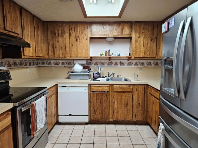 102 Stubblefield Dr, Elgin, TX 78621 - kitchen with stainless steel appliances, a sink, under cabinet range hood, brown cabinets, and light countertops