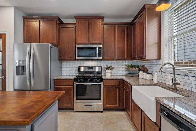 168 Pearl Way, Buda, TX 78610 - kitchen with stainless steel appliances, a sink, tasteful backsplash, dark stone countertops, and light tile patterned floors