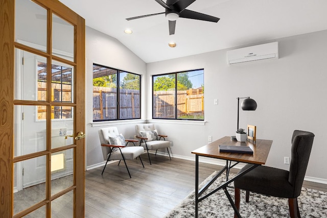 office space with a wall unit AC, vaulted ceiling, wood finished floors, baseboards, and a ceiling fan