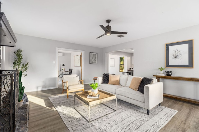 living room featuring wood finished floors, ceiling fan, and baseboards