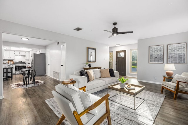 living room featuring dark wood finished floors, baseboards, and a ceiling fan