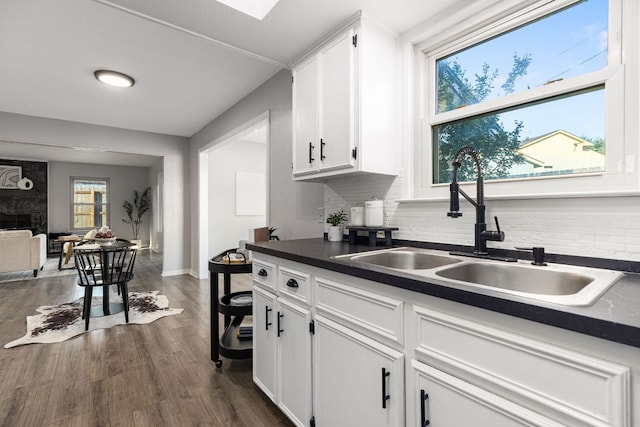 kitchen featuring a sink, dark countertops, white cabinetry, and tasteful backsplash