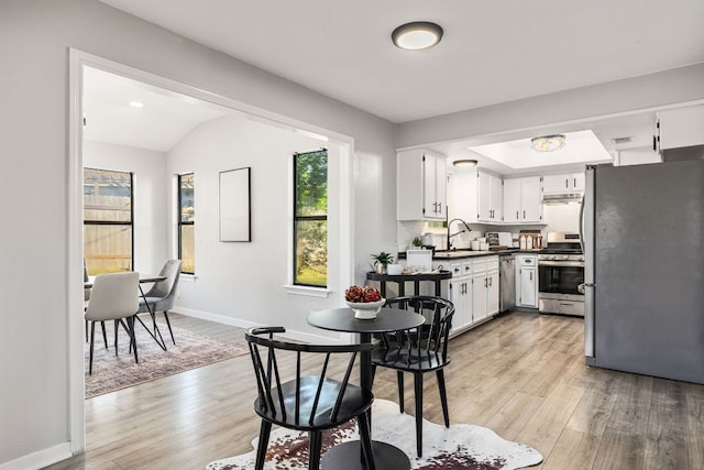 kitchen featuring stainless steel appliances, light wood finished floors, white cabinetry, and baseboards