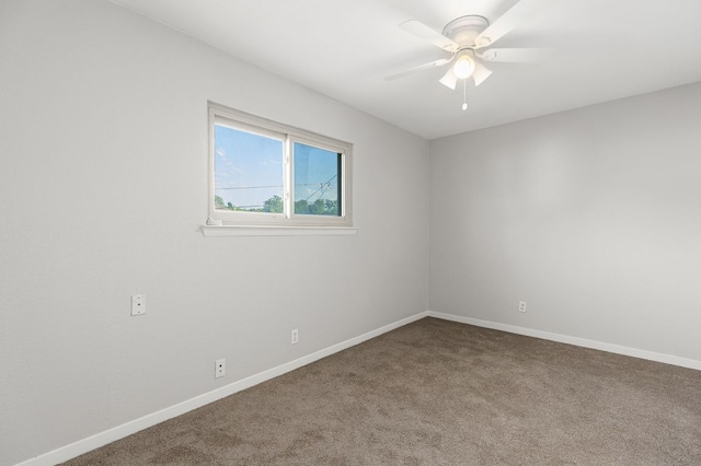 carpeted spare room featuring ceiling fan and baseboards