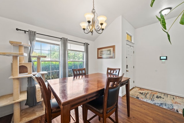 dining space featuring lofted ceiling, a chandelier, wood finished floors, and baseboards