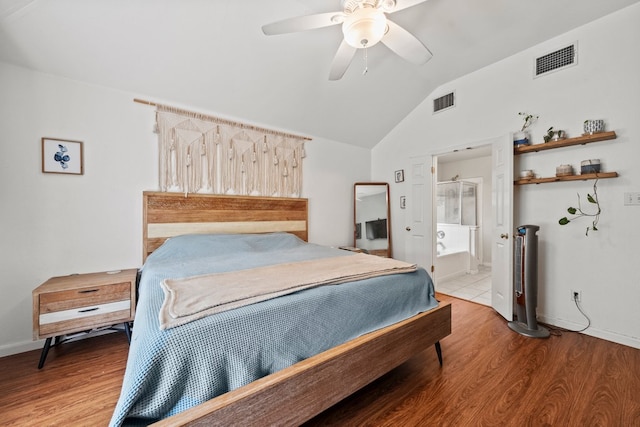 bedroom featuring lofted ceiling, wood finished floors, connected bathroom, baseboards, and ceiling fan