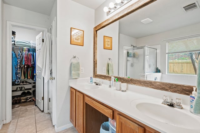 bathroom featuring a stall shower, double vanity, tile patterned floors, and a spacious closet