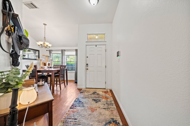 entrance foyer with a chandelier, wood finished floors, and baseboards