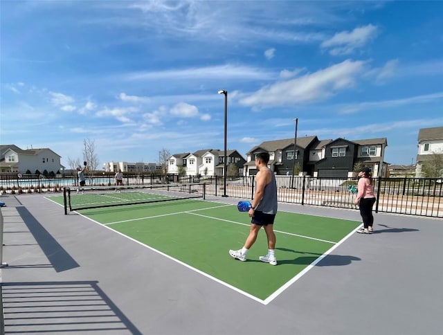 view of tennis court featuring a residential view and fence