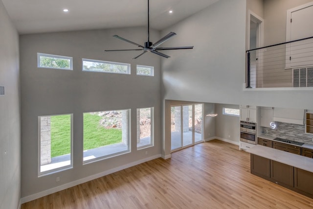 625 Desert Rose N, Horseshoe Bay, TX 78657 - unfurnished living room featuring high vaulted ceiling, light wood-style floors, plenty of natural light, baseboards, and a ceiling fan