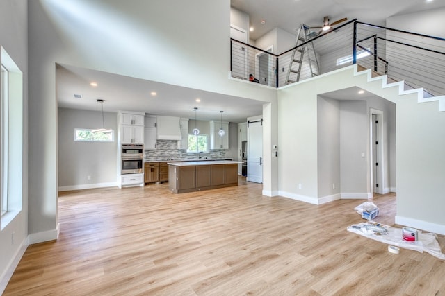625 Desert Rose N, Horseshoe Bay, TX 78657 - unfurnished living room featuring a towering ceiling, baseboards, light wood finished floors, recessed lighting, and stairs
