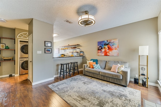 2414 Longview St Unit 208, Austin, TX 78705 - living area featuring estacked washer and dryer, wood finished floors, a textured ceiling, and baseboards