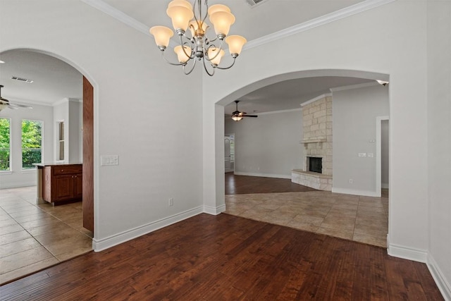 105 Longhorn Cavern Cv, Georgetown, TX 78633 - unfurnished dining area with a ceiling fan, hardwood / wood-style floors, crown molding, a stone fireplace, and a chandelier