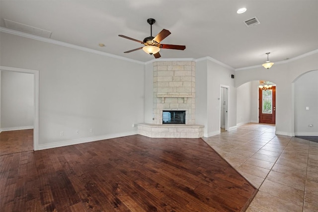 105 Longhorn Cavern Cv, Georgetown, TX 78633 - unfurnished living room with arched walkways, a ceiling fan, ornamental molding, a stone fireplace, and baseboards