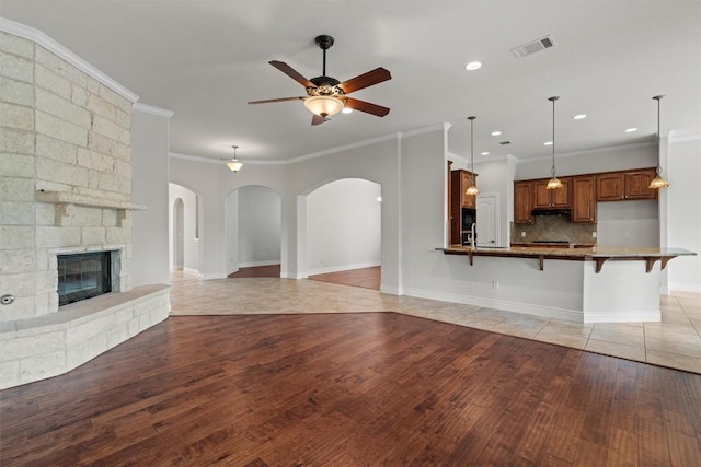 105 Longhorn Cavern Cv, Georgetown, TX 78633 - unfurnished living room featuring light wood-type flooring, ornamental molding, ceiling fan, baseboards, and a fireplace
