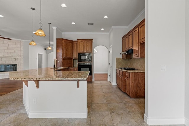 105 Longhorn Cavern Cv, Georgetown, TX 78633 - kitchen with black appliances, arched walkways, a sink, a breakfast bar, and light stone counters