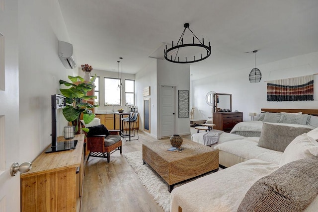 living room featuring light wood-style flooring, a chandelier, a wall unit AC, and baseboards