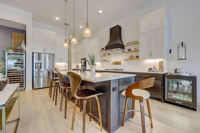 kitchen featuring stainless steel fridge, beverage cooler, custom range hood, light wood-type flooring, and recessed lighting