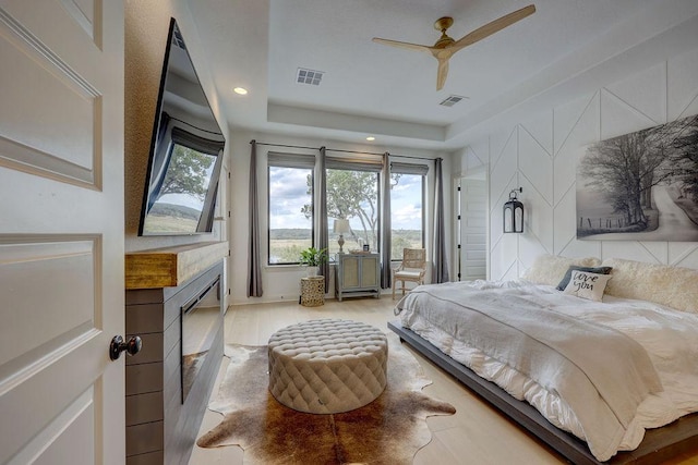 bedroom with multiple windows, a fireplace, access to exterior, wood finished floors, and recessed lighting