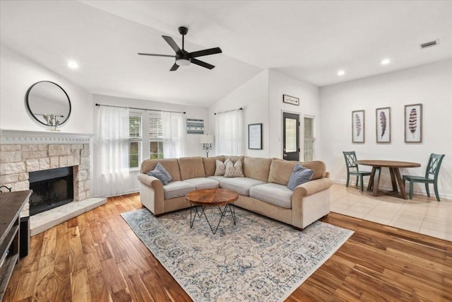 living area featuring a ceiling fan, lofted ceiling, wood finished floors, recessed lighting, and a stone fireplace
