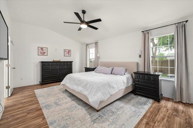 bedroom with wood finished floors, multiple windows, lofted ceiling, and ceiling fan