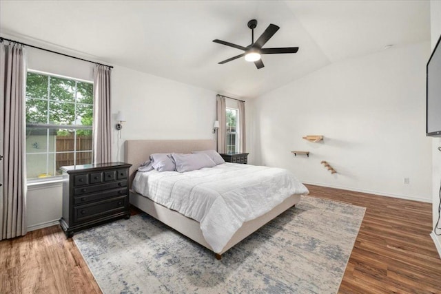 bedroom with vaulted ceiling, wood finished floors, ceiling fan, and baseboards