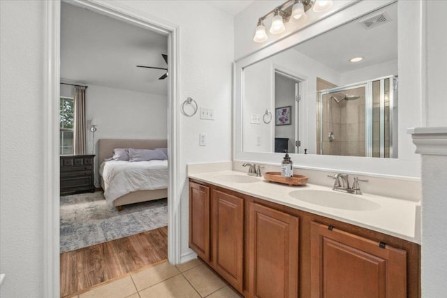 ensuite bathroom with a stall shower, tile patterned flooring, and double vanity