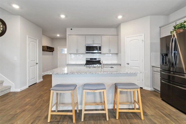 118 Ballyneal Ln, San Marcos, TX 78666 - kitchen with appliances with stainless steel finishes, decorative backsplash, a kitchen breakfast bar, dark wood-style flooring, and recessed lighting