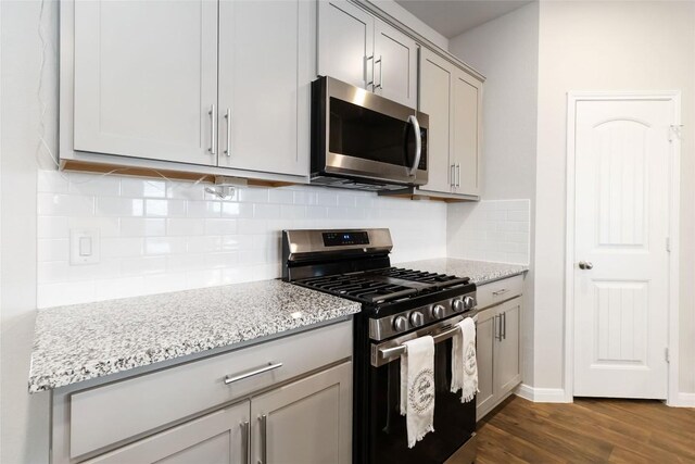 118 Ballyneal Ln, San Marcos, TX 78666 - kitchen featuring appliances with stainless steel finishes, gray cabinets, dark wood finished floors, and light stone countertops