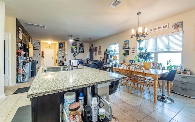 1714 Deodara Dr, Cedar Park, TX 78613 - kitchen featuring light tile patterned flooring, ceiling fan, a chandelier, an island with sink, and light stone countertops