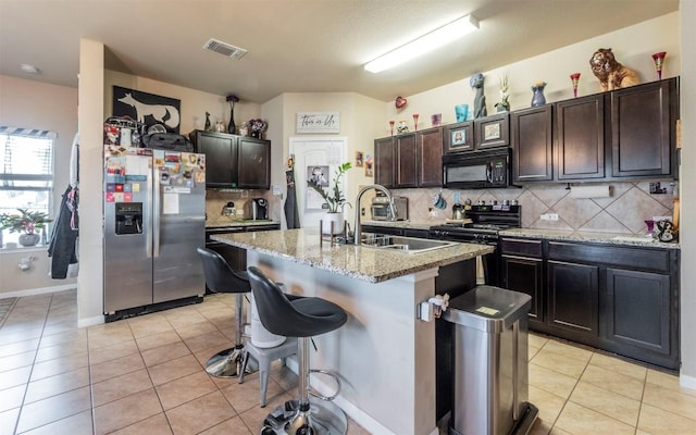 1714 Deodara Dr, Cedar Park, TX 78613 - kitchen featuring black appliances, decorative backsplash, light tile patterned floors, a breakfast bar, and light stone counters